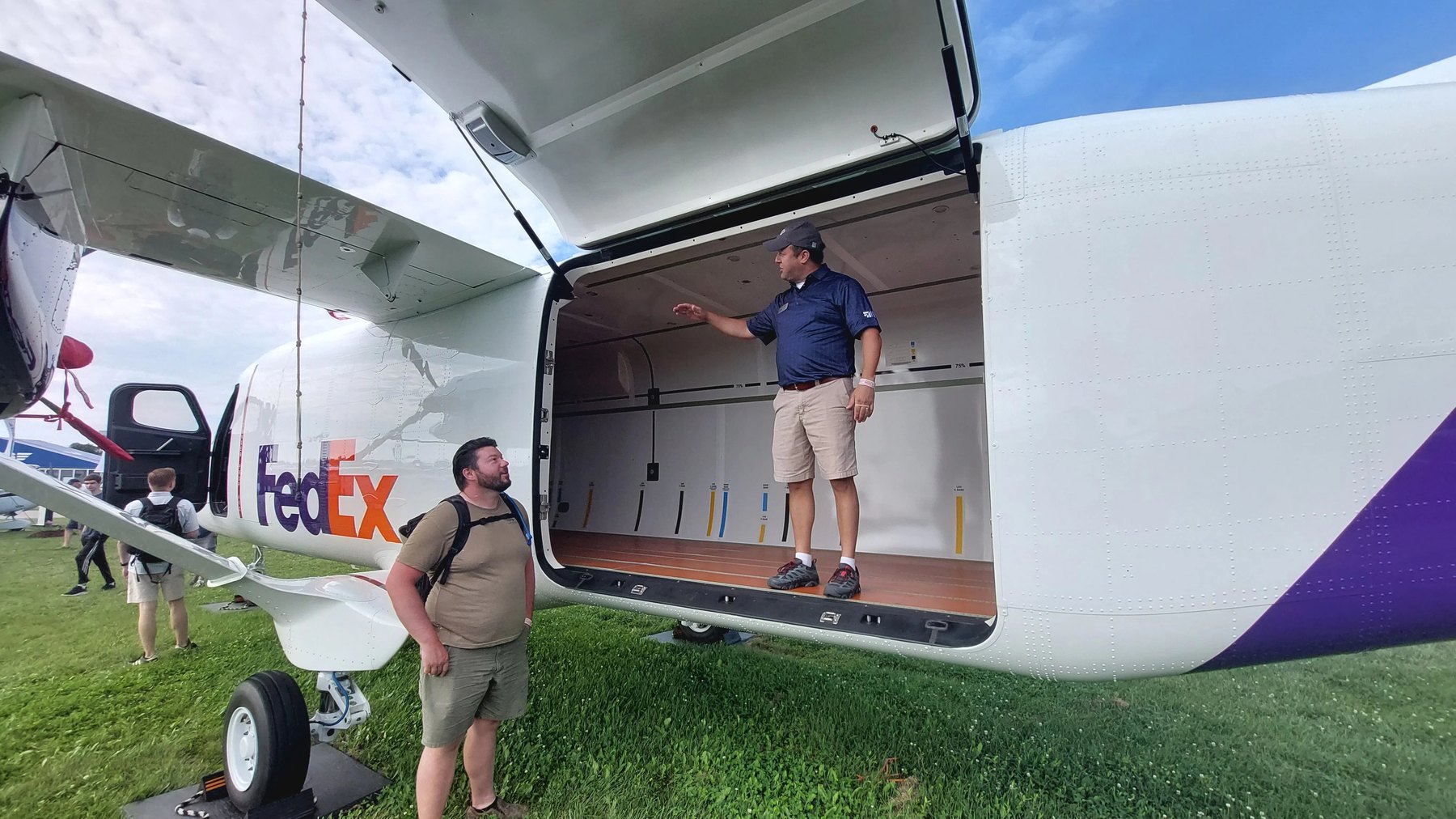 A Cessna SkyCourier with its large cargo door open and a person standing inside the hold
