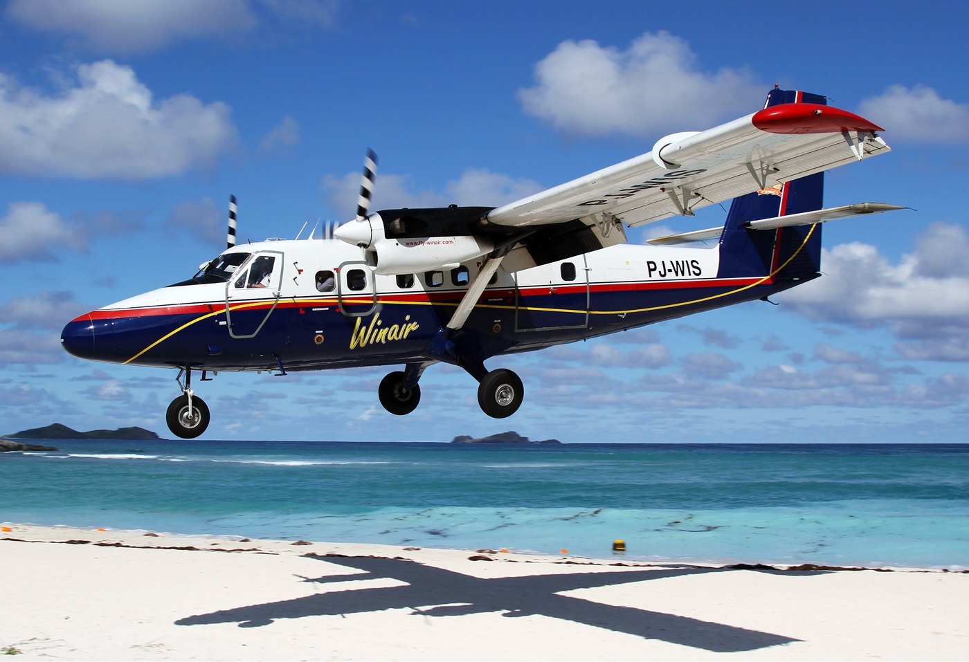 A DHC-6 Twin Otter landing low over a beach